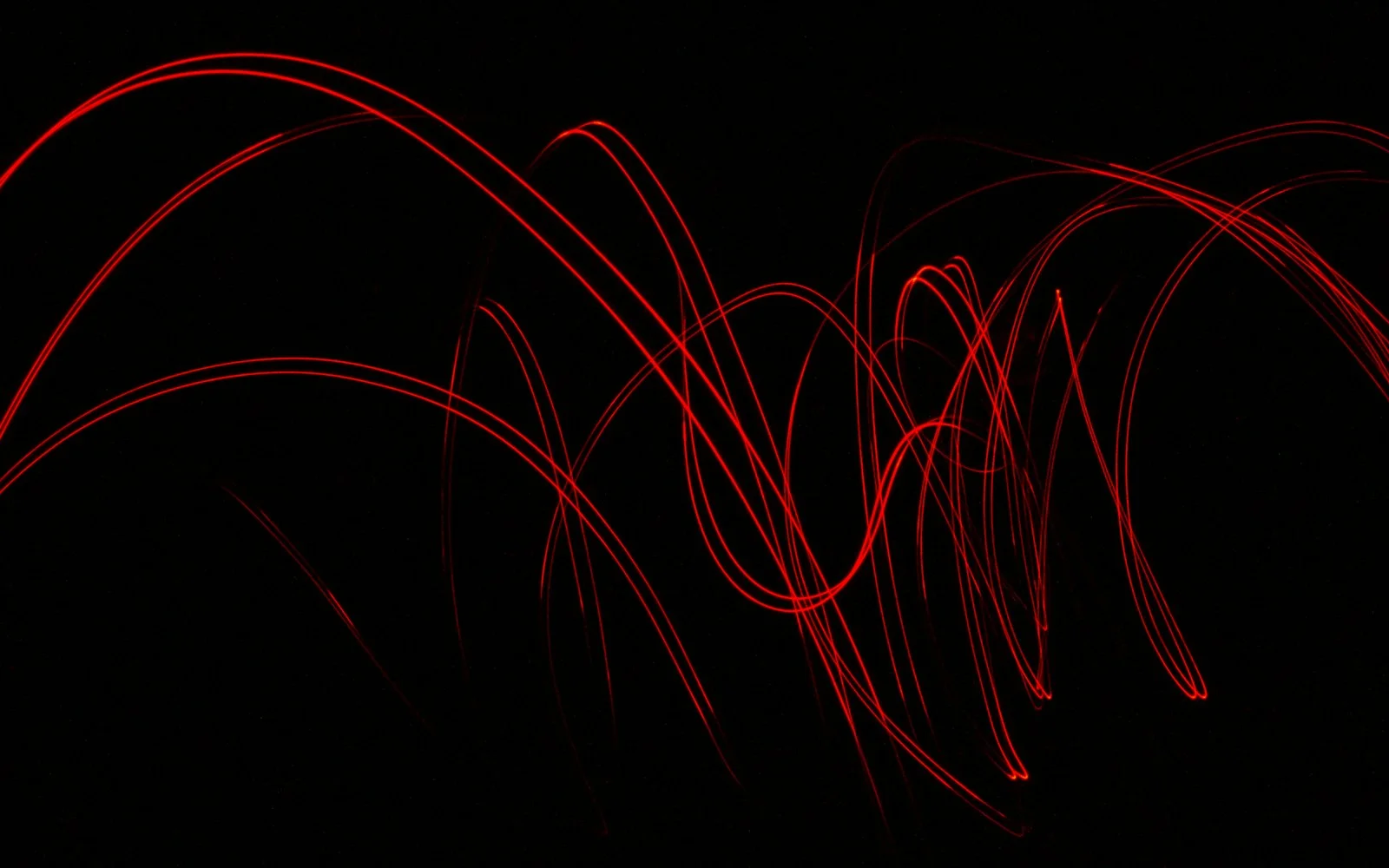 Red light trails looping and crossing over a black background.